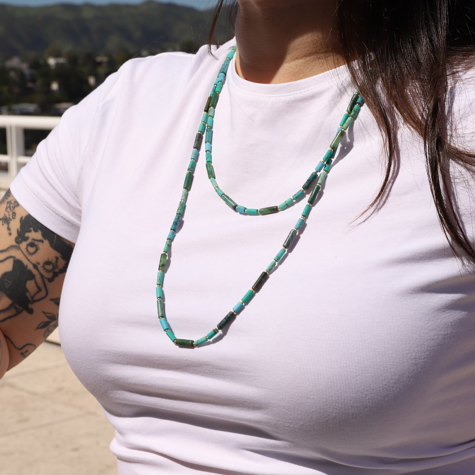 Turquoise and green beaded necklace on a white background