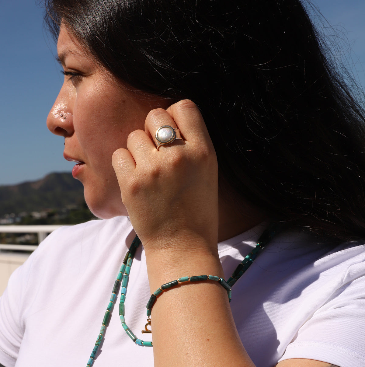 Person wearing a ring and white shirt with a scenic background
