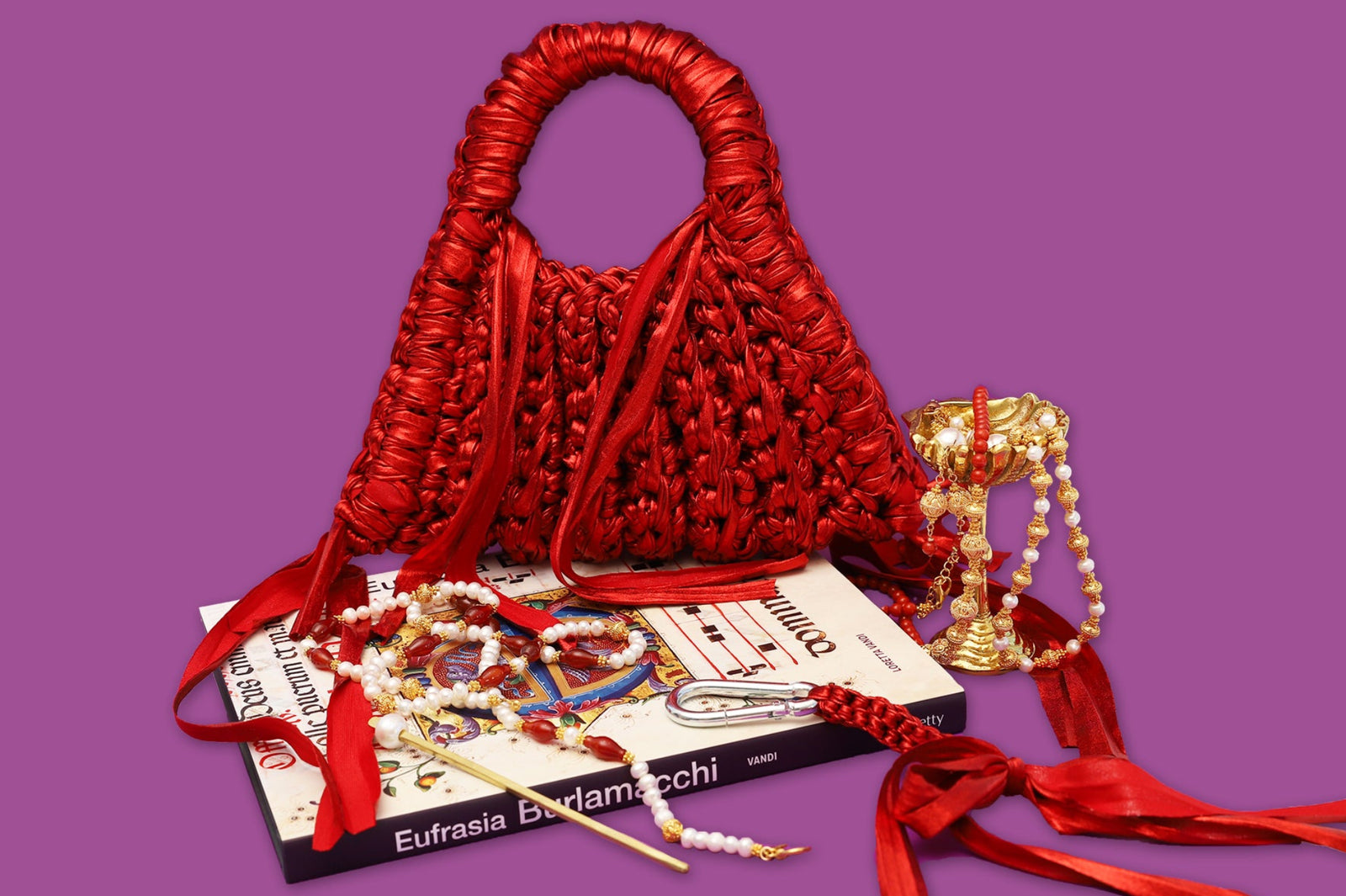 Red woven handbag with jewelry on a purple background