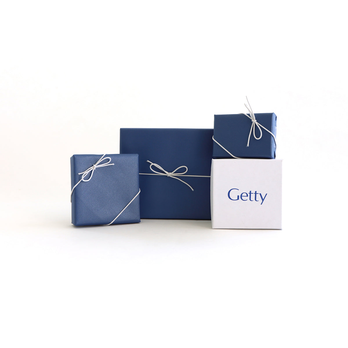 3 jewelry boxes gift wrapped in blue wrapping paper with thin white bows, and 1 white jewelry box unwrapped with Getty logo branding