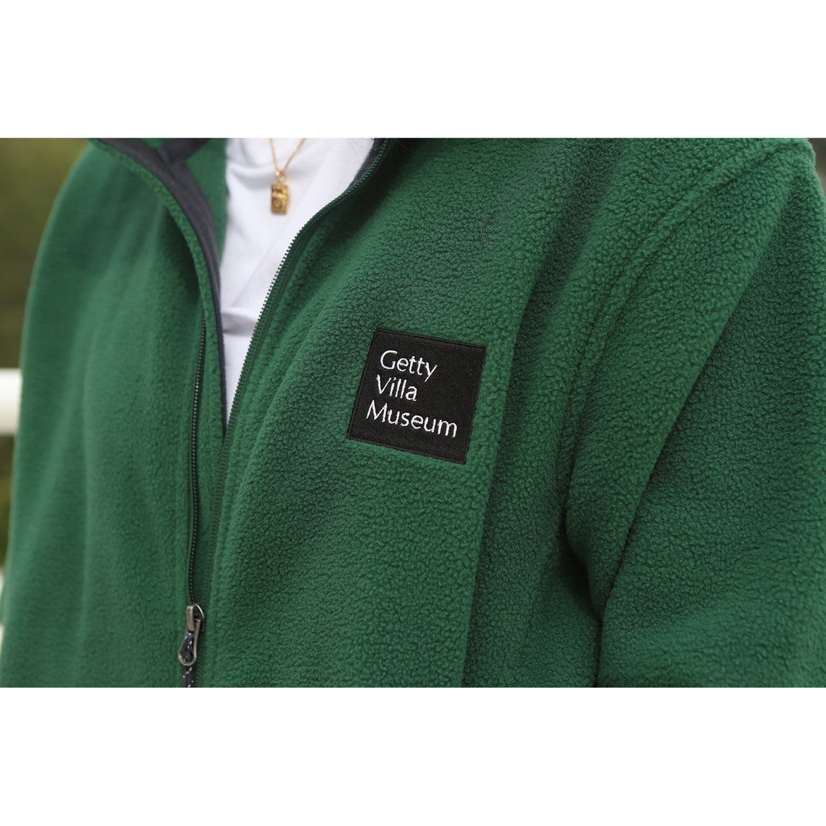 Green fleece jacket with Getty Villa Museum patch on a white background