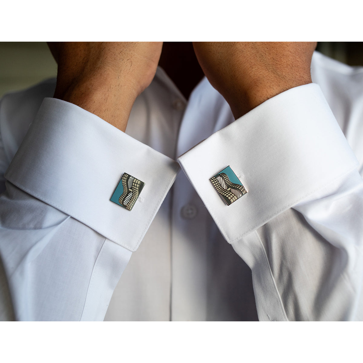 Close-up of a white shirt with patterned cufflinks on a blurred background
