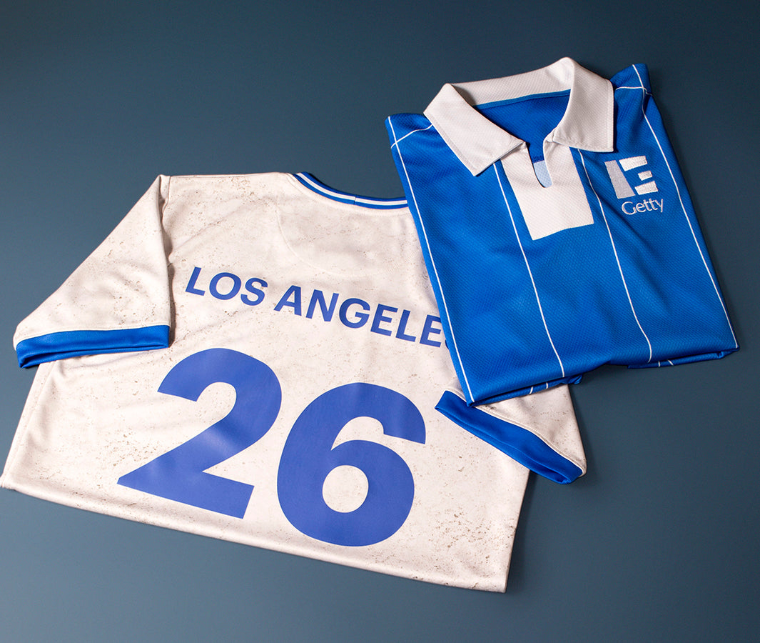White sports jersey with blue accents and 'Los Angeles 26' printed on a dark gray background