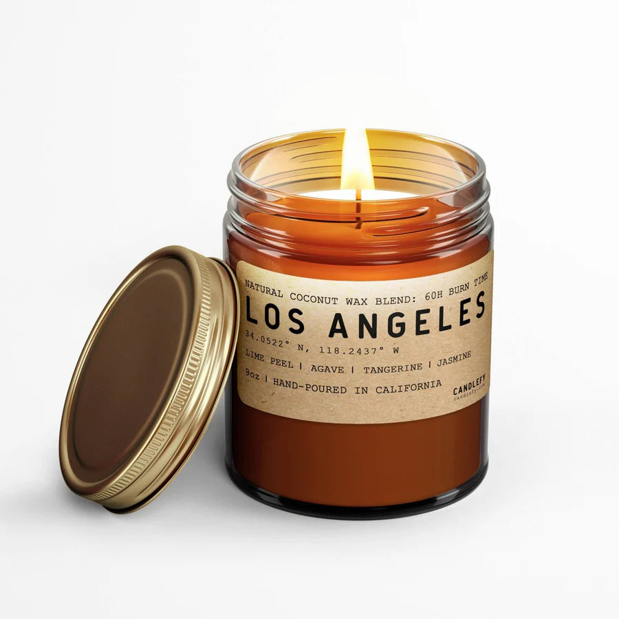 An 8 oz amber glass jar candle with a golden brass lid, labeled 'LOS ANGELES' and scented with citrusy lime peel and tangerine, balanced with jasmine and agave notes.