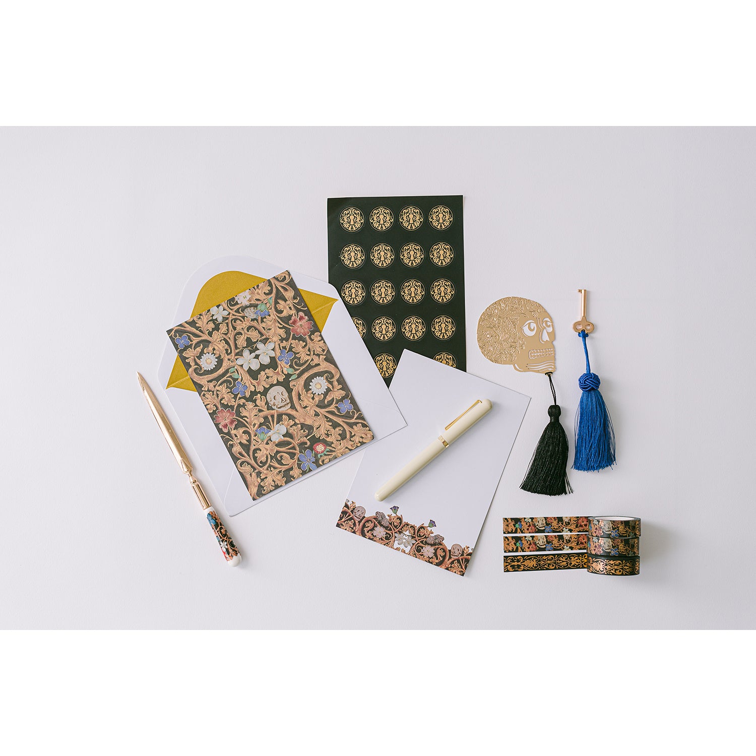 A lacquer keepsake box with a blue velvet interior, containing stationery items including writing sheets, metallic lined envelopes, stickers, washi tape, a metal bookmark, and a ceramic letter opener.