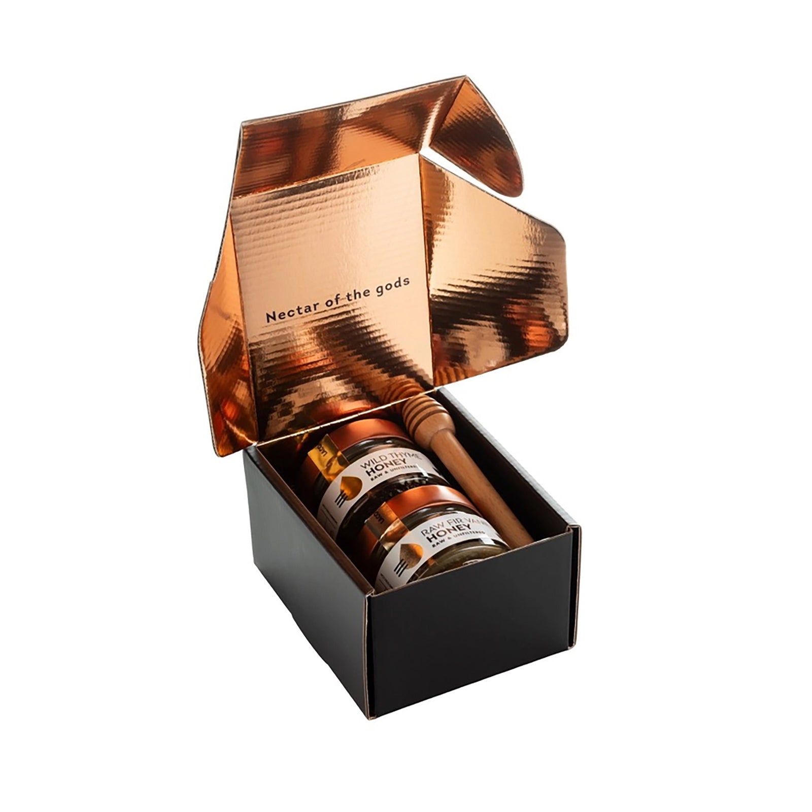 A honey gift set featuring two glass jars of honey with copper lids, a wooden honey dipper, and a black presentation box with a metallic circular logo, all on a reflective white surface.
