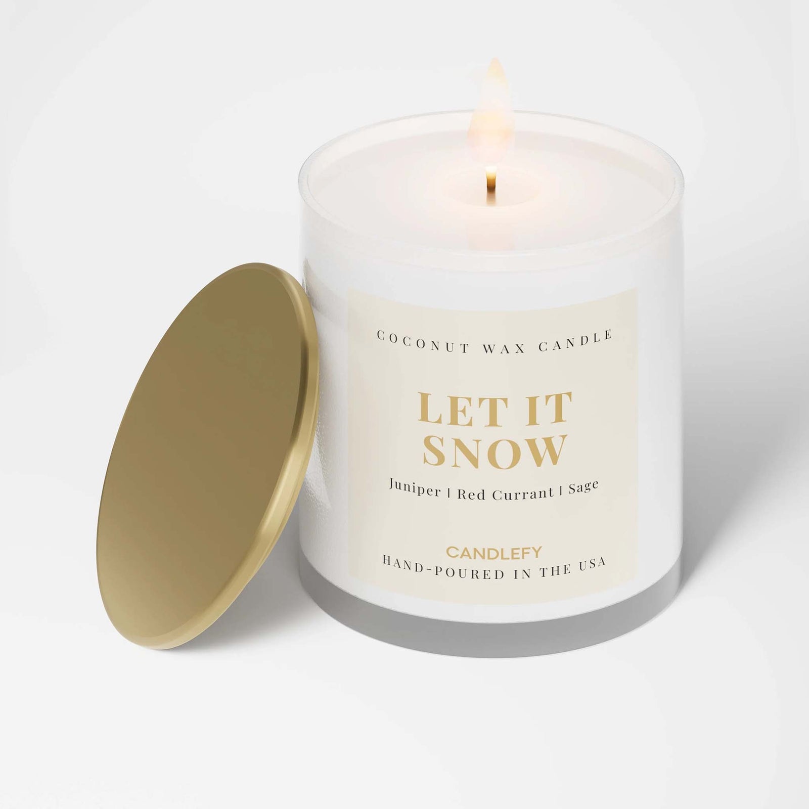 Coconut wax candle labeled 'Let It Snow' with a gold lid on a white background