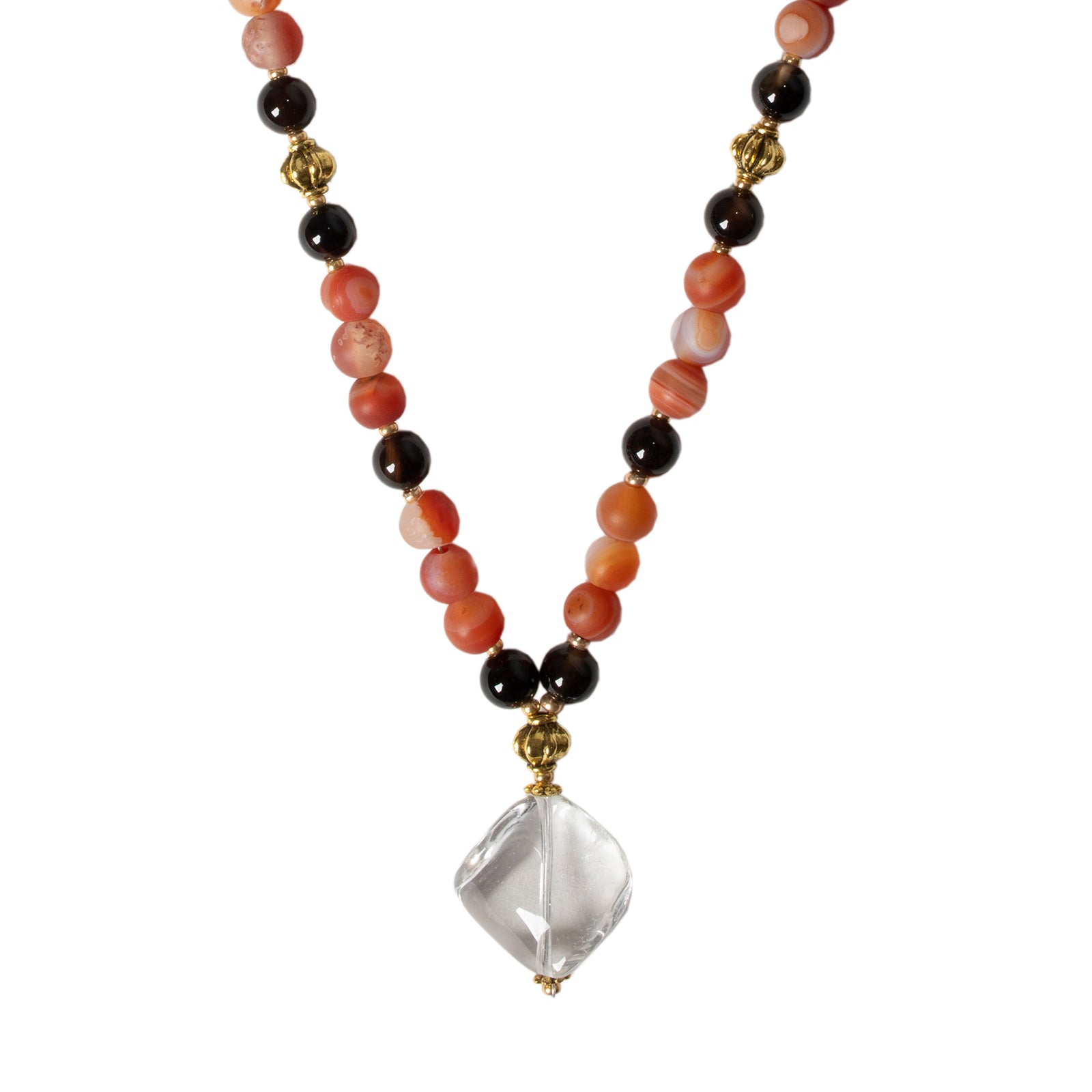 A necklace featuring a clear rock crystal pendant with carnelian and agate beads, with gold plated brass accents.