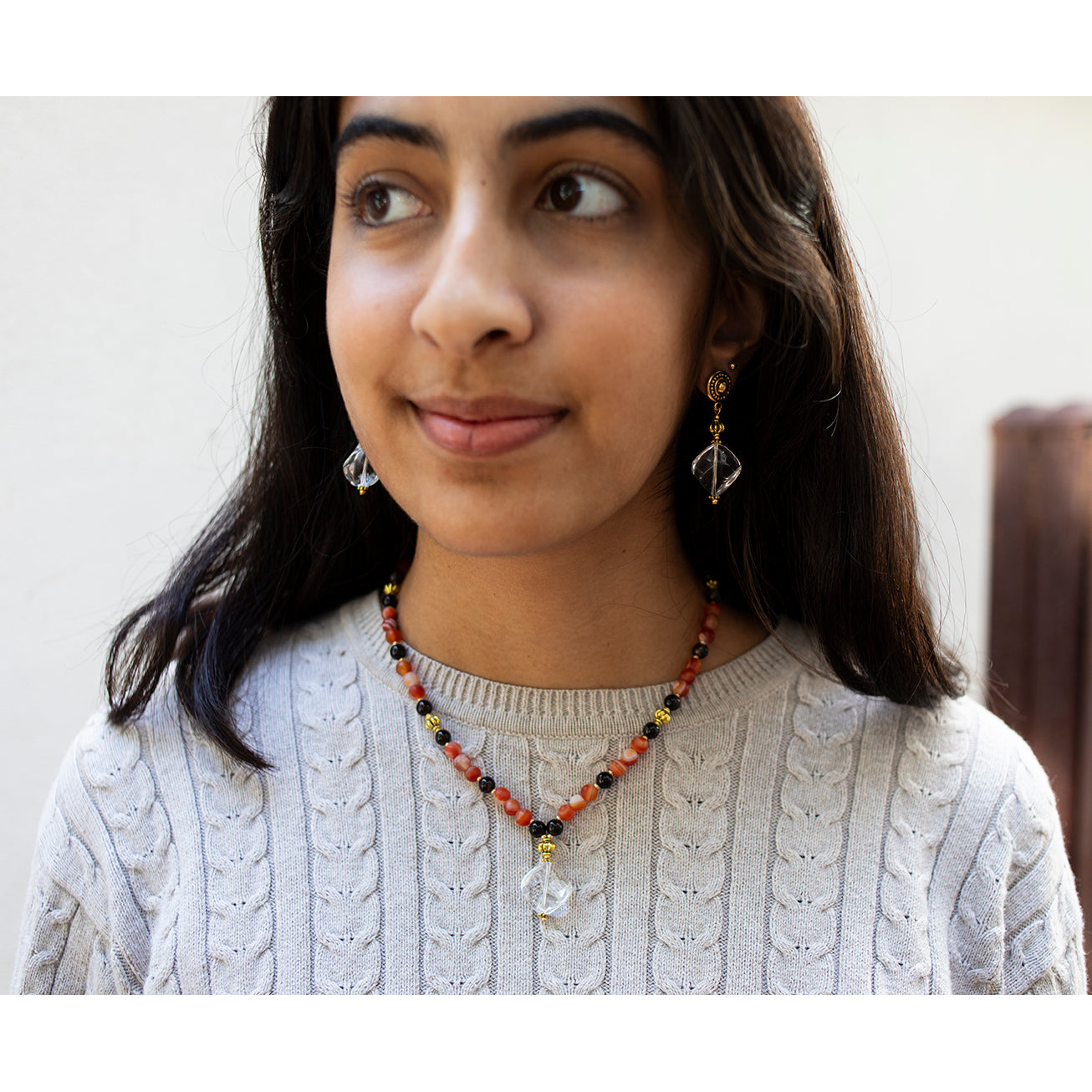 A pair of gold-plated brass earrings with large crystal drops, featuring intricate detailing and a vintage design.