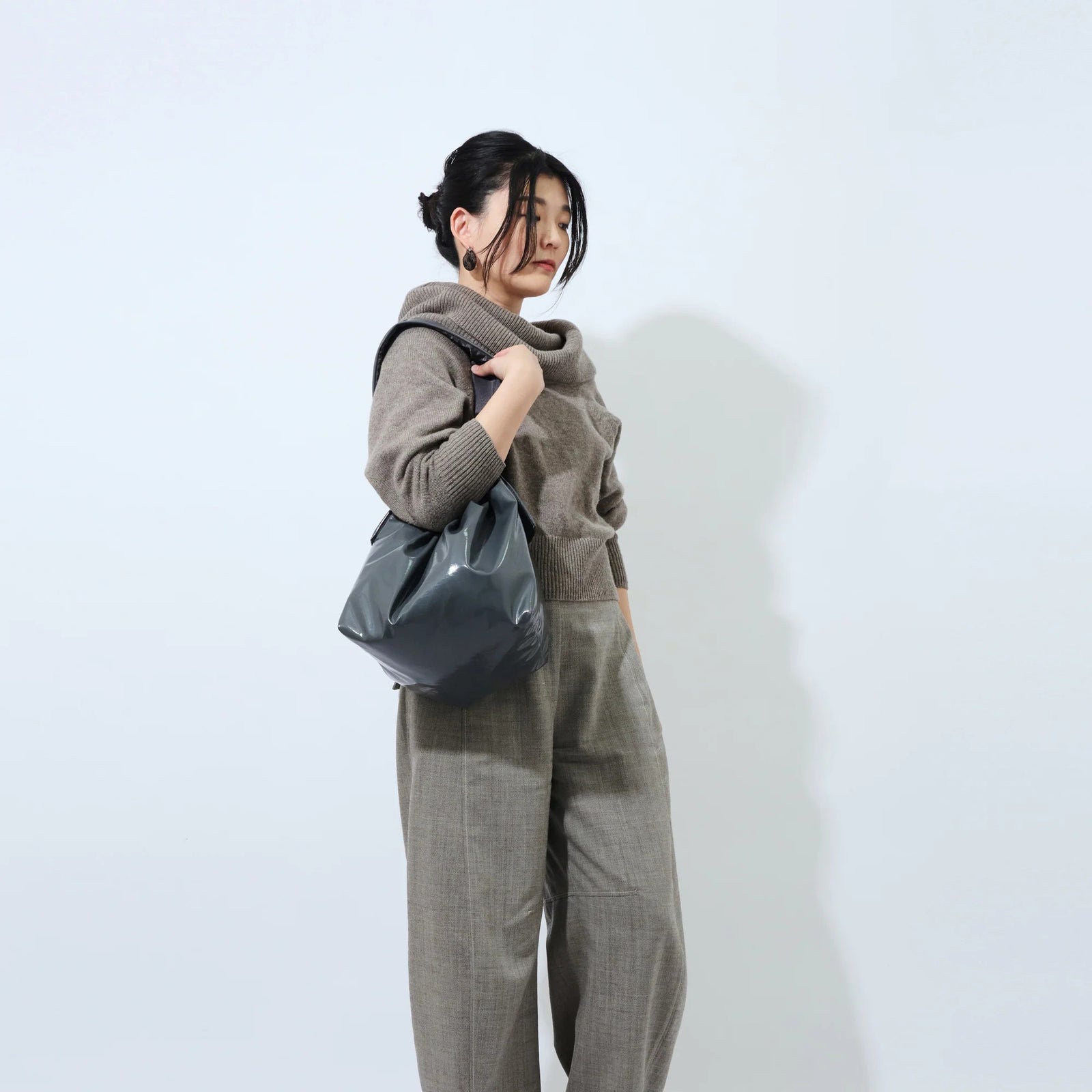 Gray handbag with a drawstring top on a light gray background