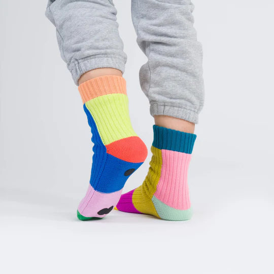 Colorful socks worn with gray pants on a light gray background