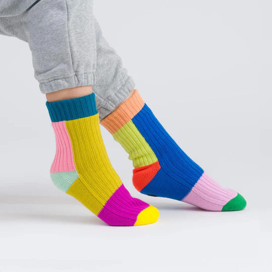 Colorful striped socks worn with gray pants on a light background