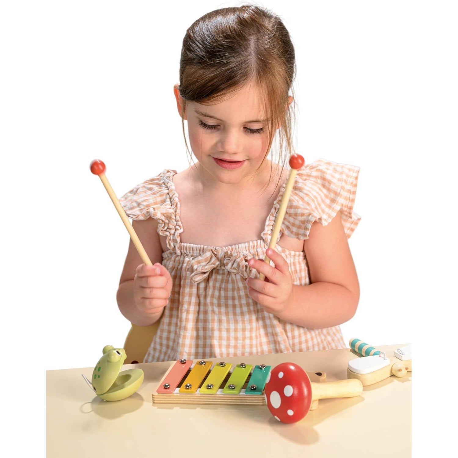 Set of colorful wooden musical instruments including a xylophone, mallets, and a bell on a white background.