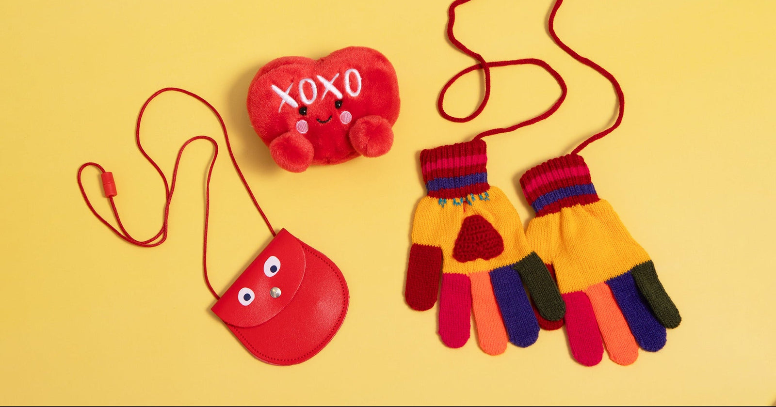 Colorful gloves with heart designs and a red pouch on a yellow background