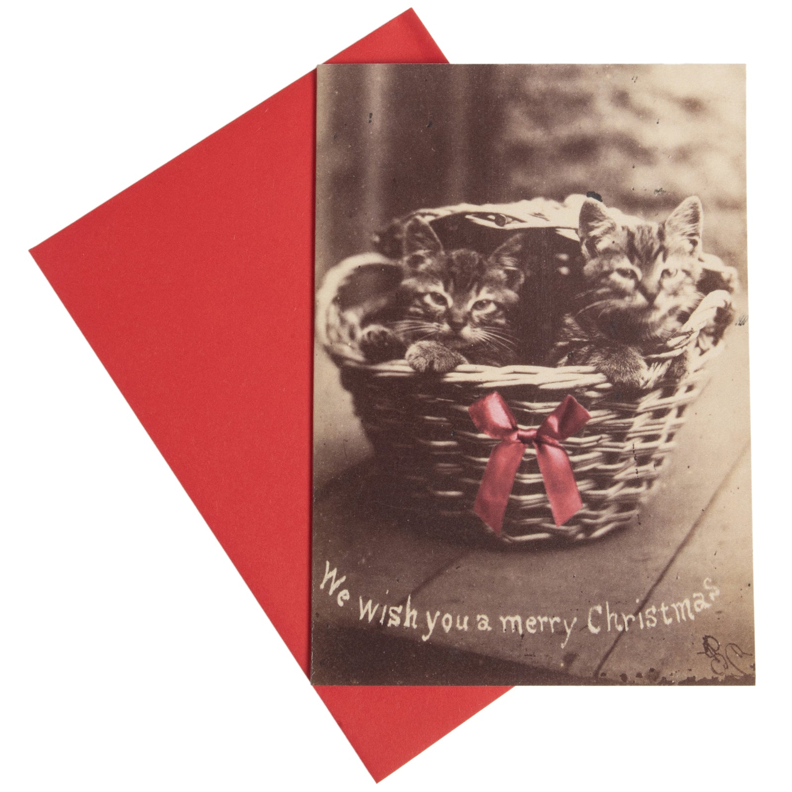 A holiday card featuring a historical photograph of two kittens in a basket with a 'We wish you a merry Christmas' caption, accompanied by a red envelope.