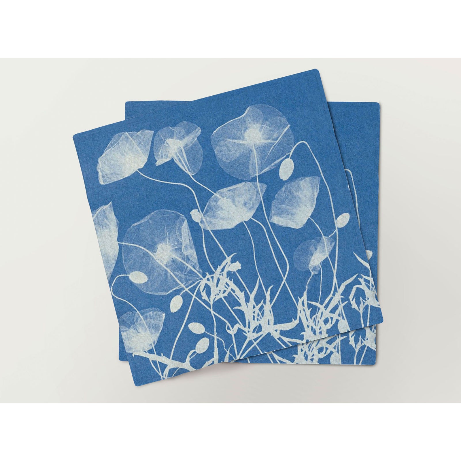 A set of six blue linen napkins, each with a different white botanical print design.