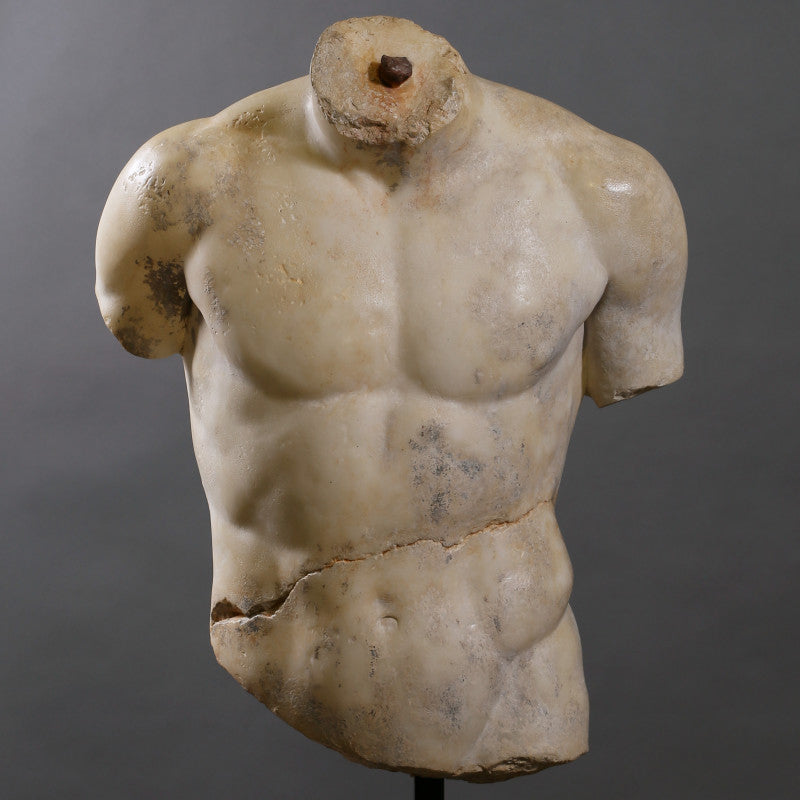 A sculpture of a torso made of alabaster and other composite materials, displayed on a stand.