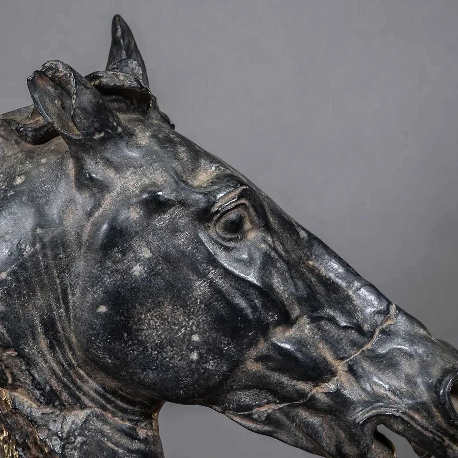 Bronze sculpture of a horse head on a stand against a white background