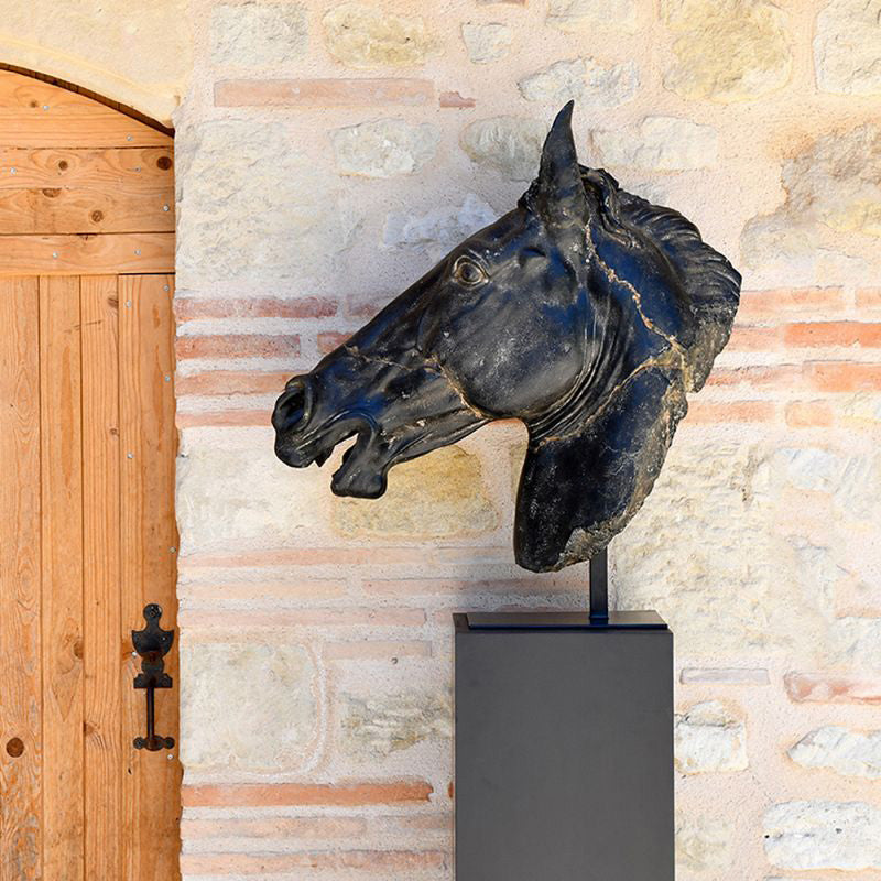A bronze sculpture of a horse's head on a wooden base with a metal stand.