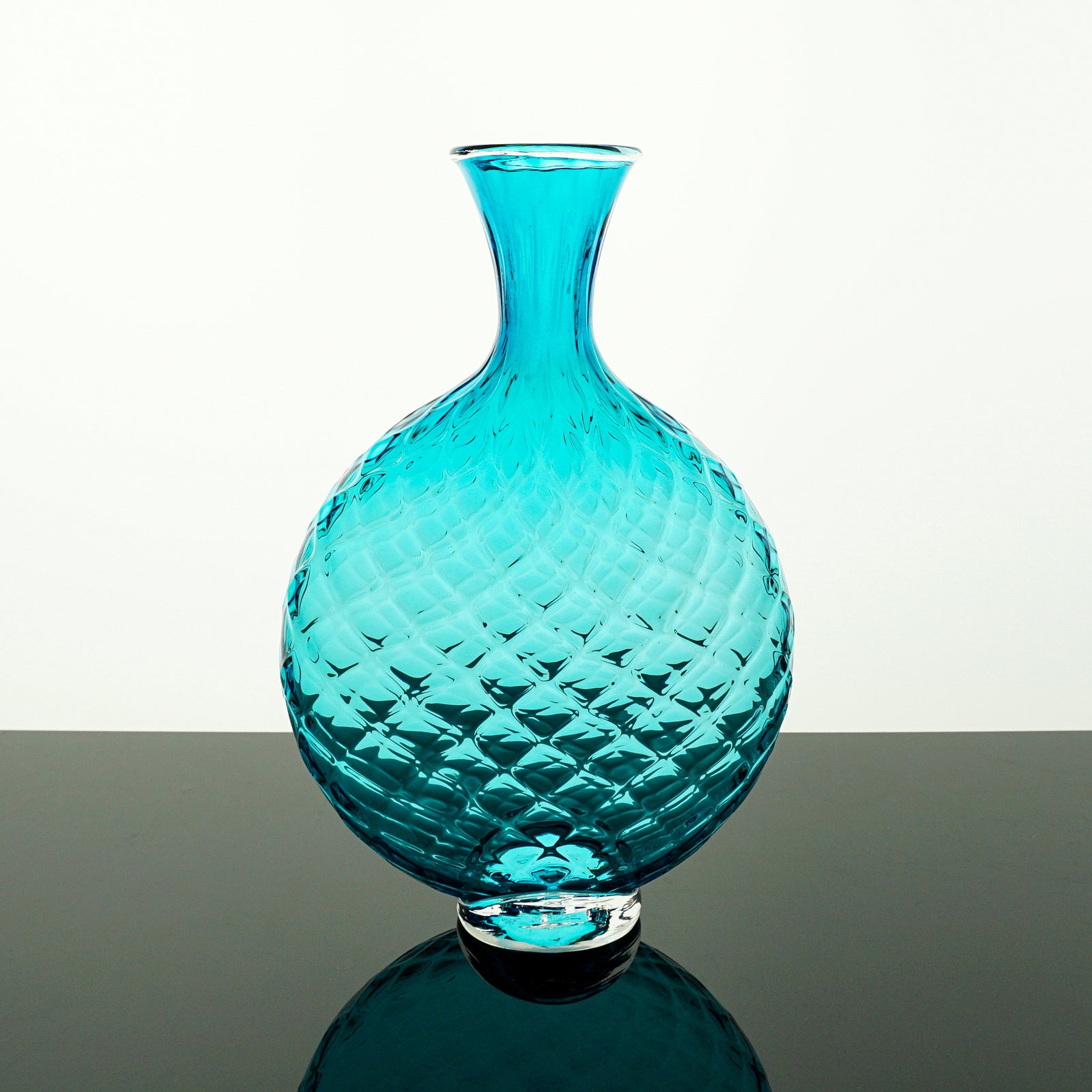 Turquoise glass vase with textured surface on a white background