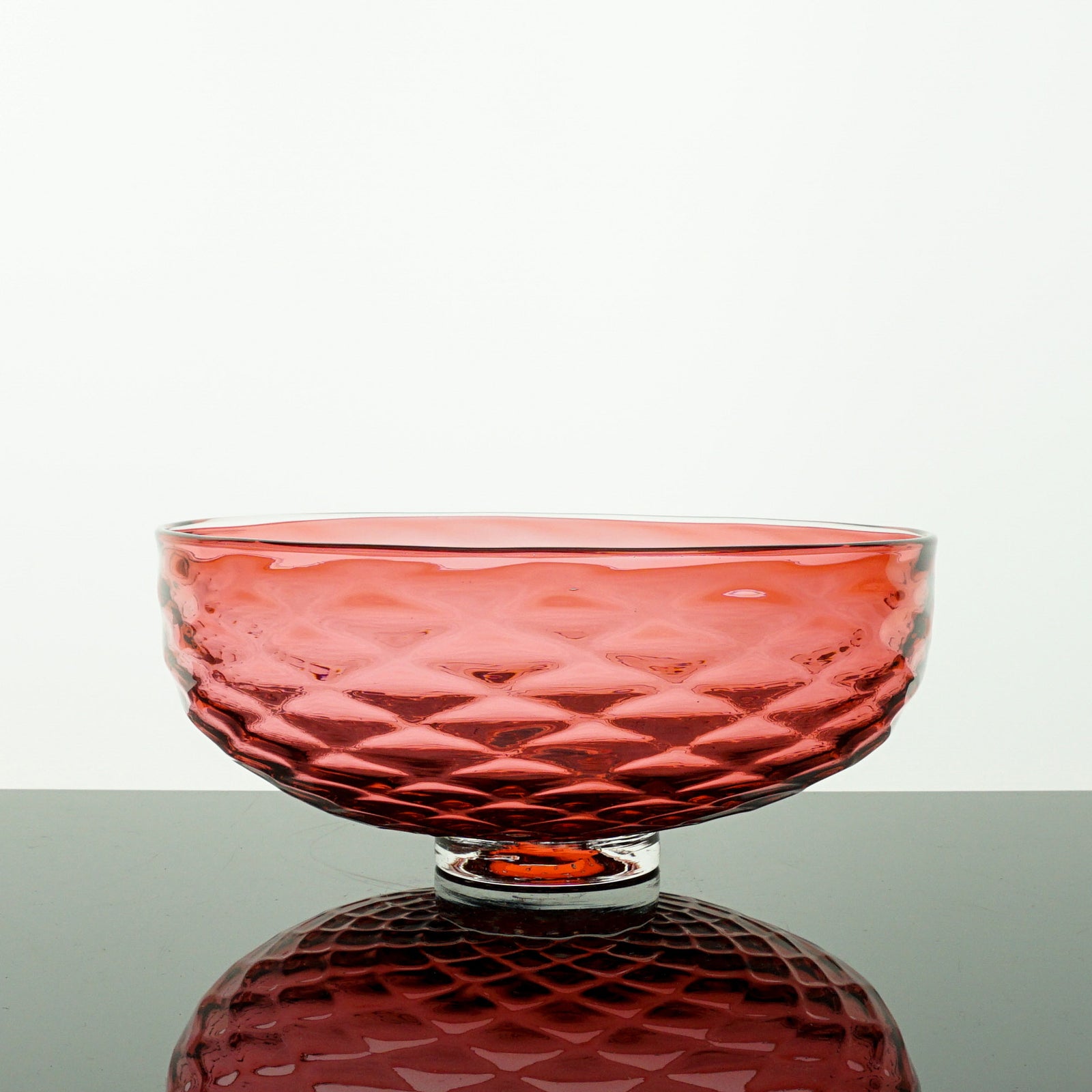 Red glass bowl with textured surface on a white background