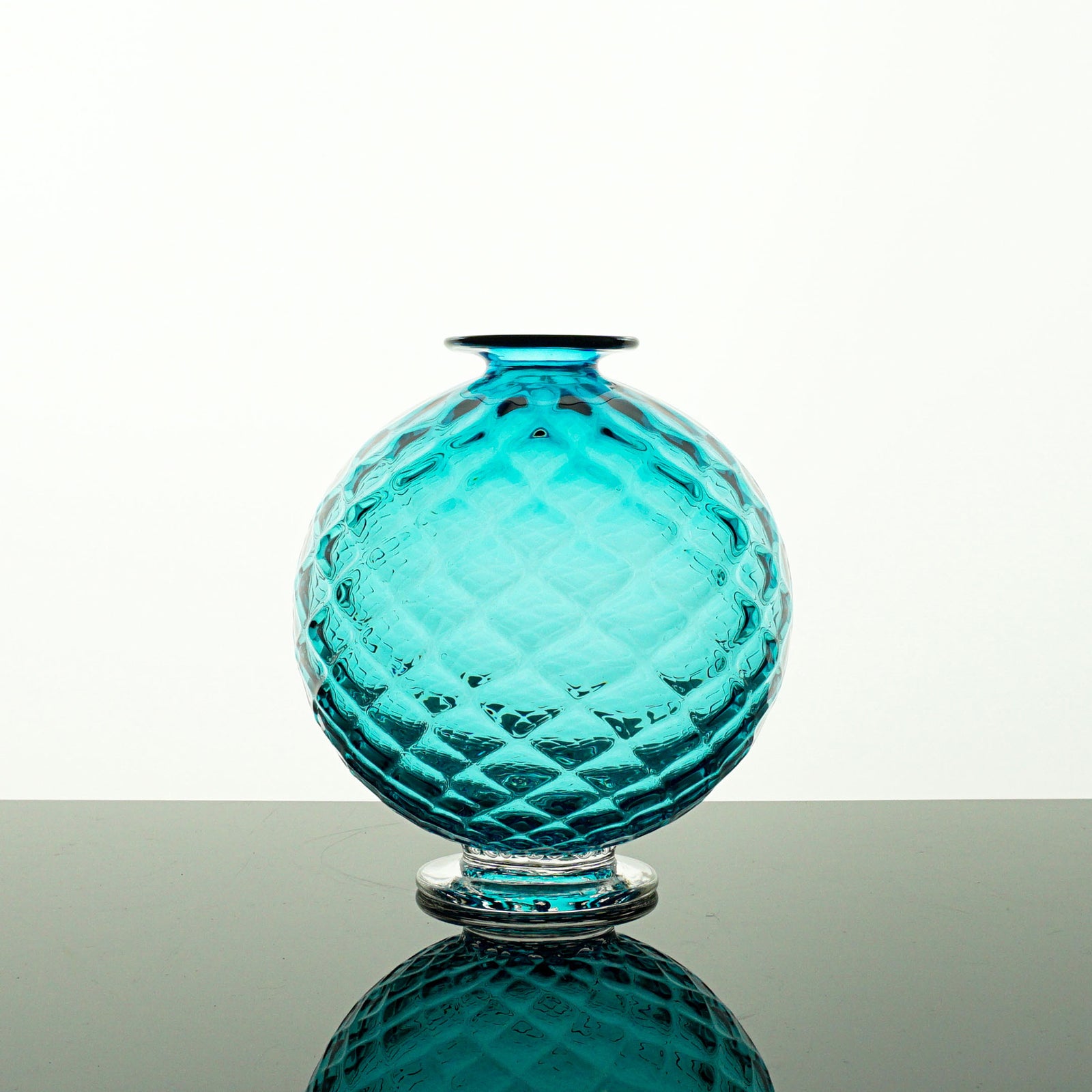 Turquoise glass vase with textured surface on a white background