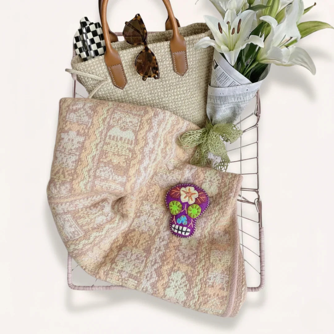 Tote bag with skull design, flowers, and a straw bag on a white background