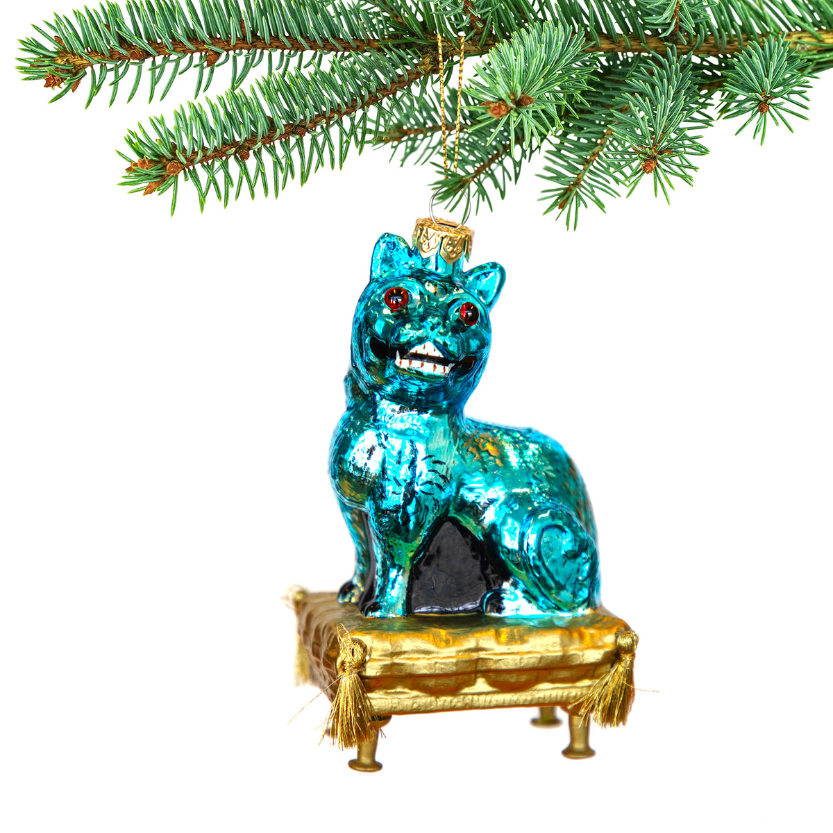 Blue glass cat ornament on a gold pedestal with red eyes, hanging from a Christmas tree.