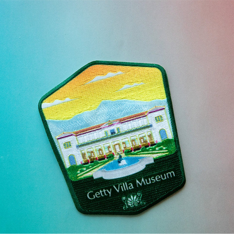 A patch depicting the Getty Villa Museum with a embroidered landscape and building illustration.