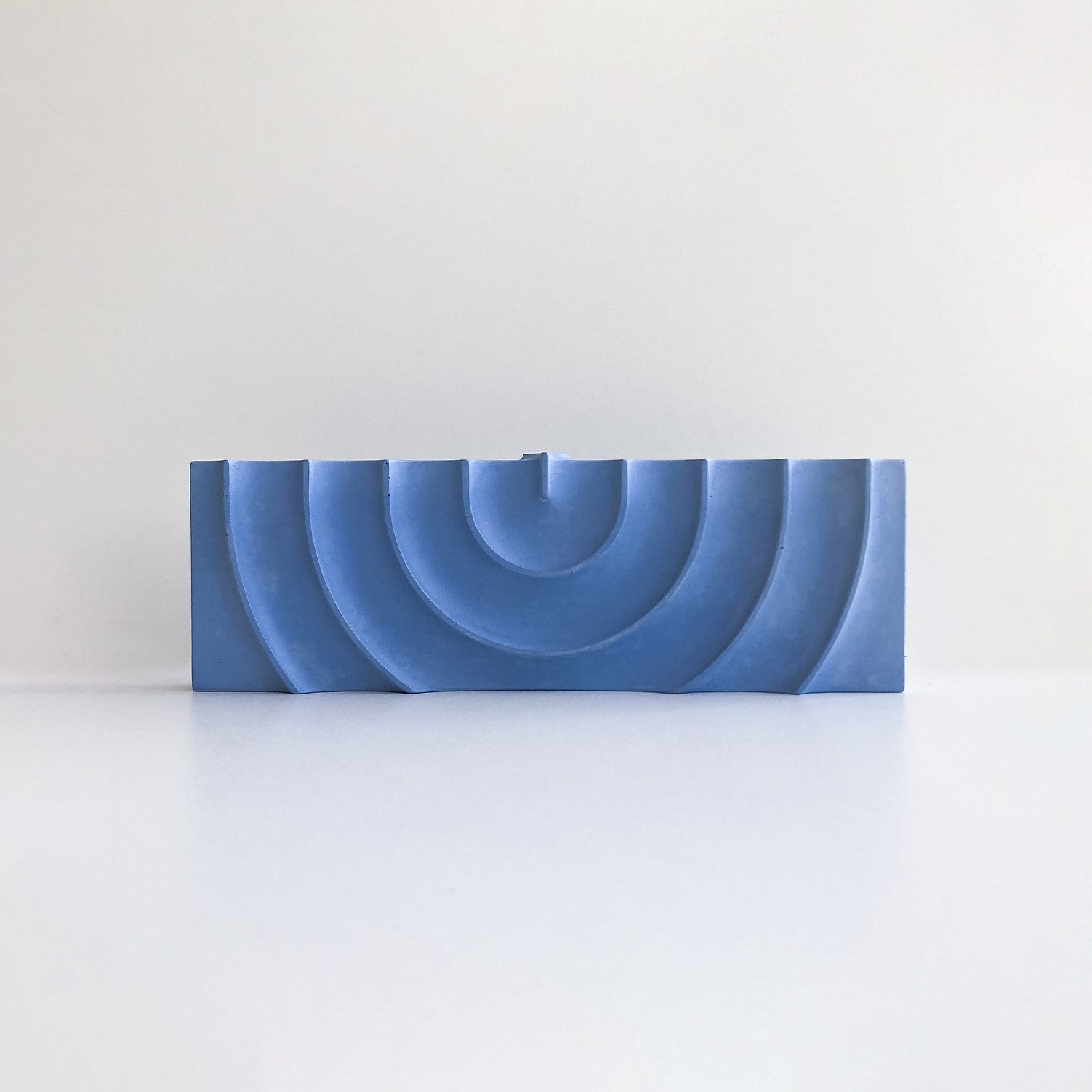 Blue plastic component with multiple holes on a light gray background