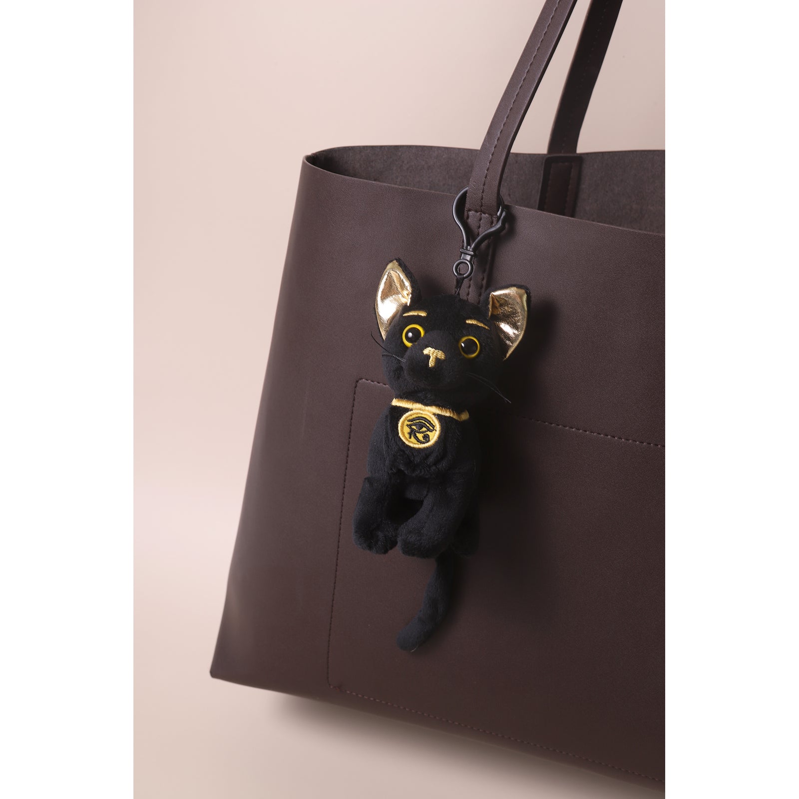 Black cat plush toy with gold accents on a white background