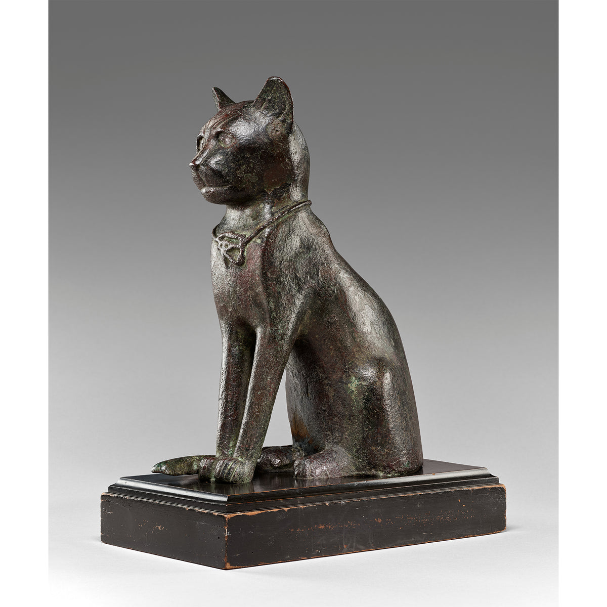 Bronze statue of a cat on a gray background