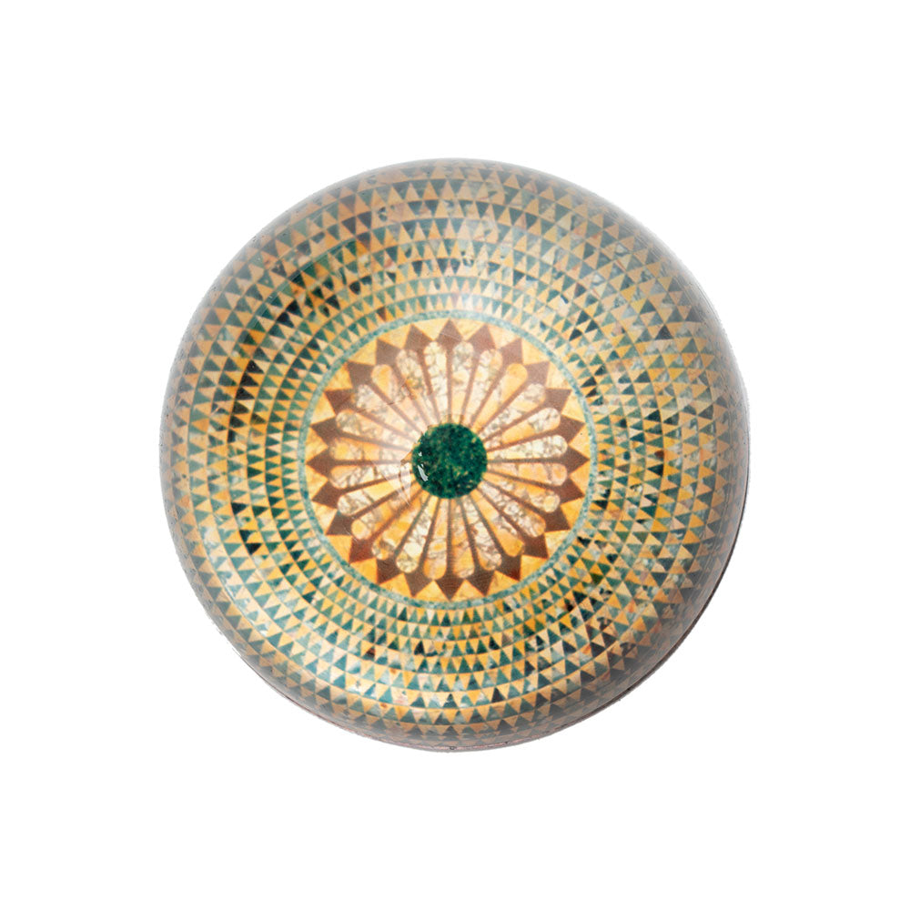A round glass paperweight with a mosaic pattern resembling a temple floor.