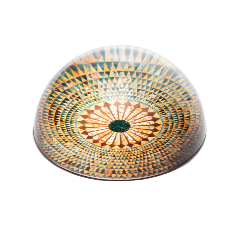 A round glass paperweight with a mosaic pattern resembling a temple floor.