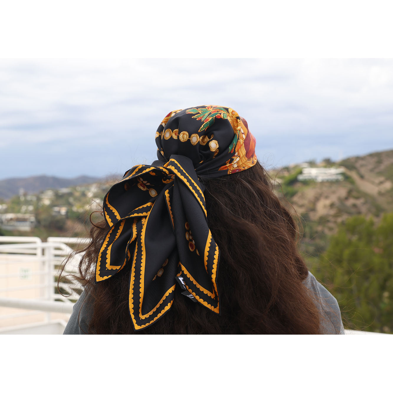A square black scarf featuring an ornate Baroque-style design with gold chains, gold oval medallions containing classical portraits, and a central painted scene with red and green accents.