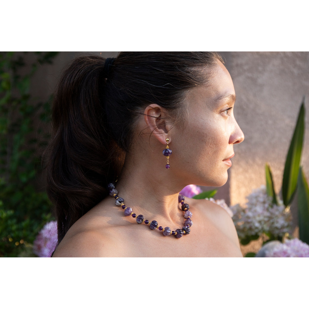 Woman wearing a necklace and earrings with a blurred floral background