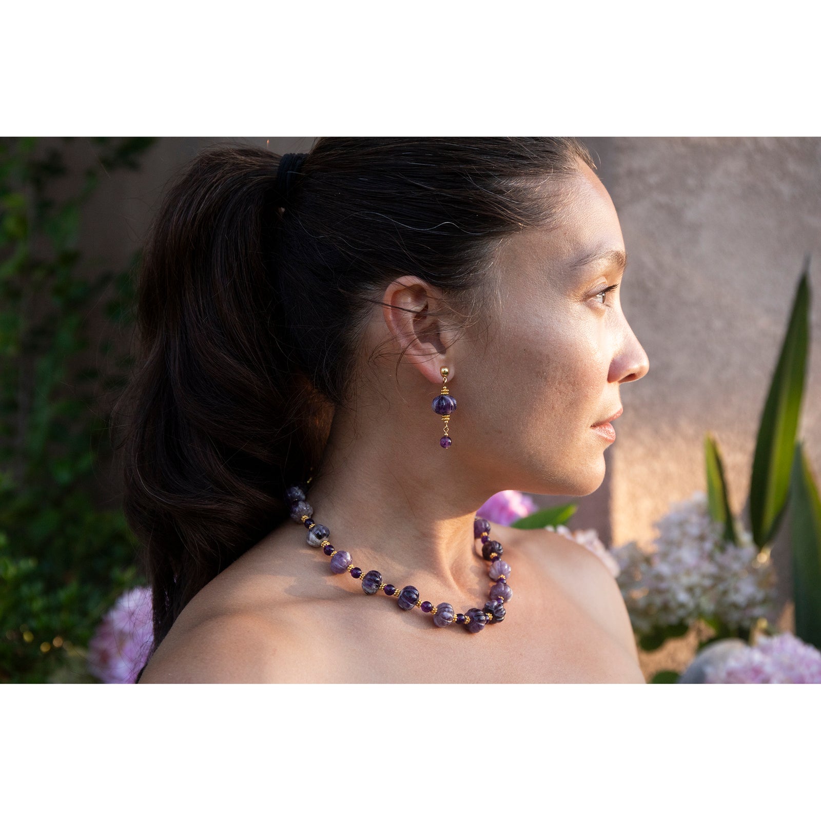 Pair of earrings with purple beads and gold accents on a white background