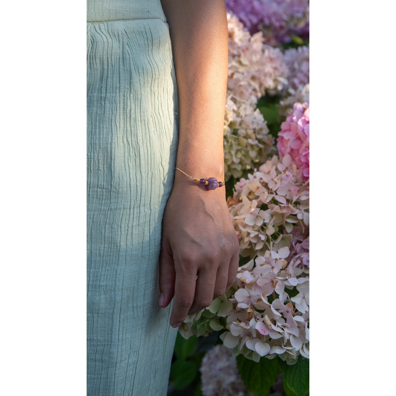 Gold bracelet with purple beads on a white background