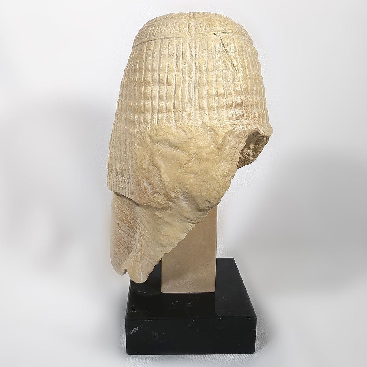 Stone sculpture of a head on a black base against a white background