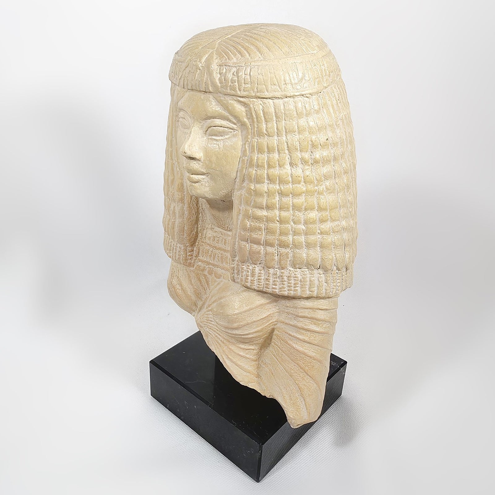 Carved stone bust of a figure with a headdress on a white background