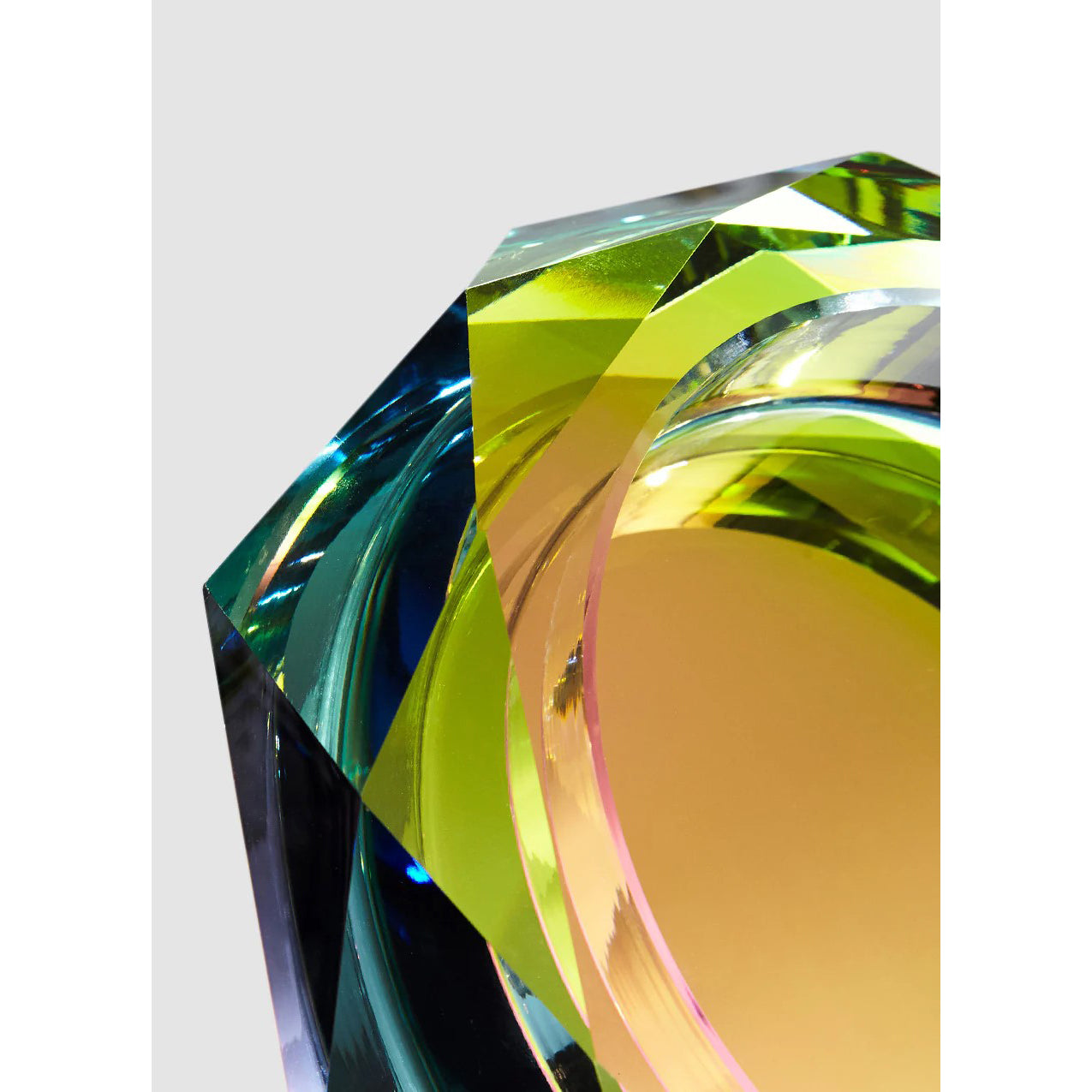 A hand cut crystal bowl with a multicolored reflective bottom, displaying a spectrum of colors when illuminated.