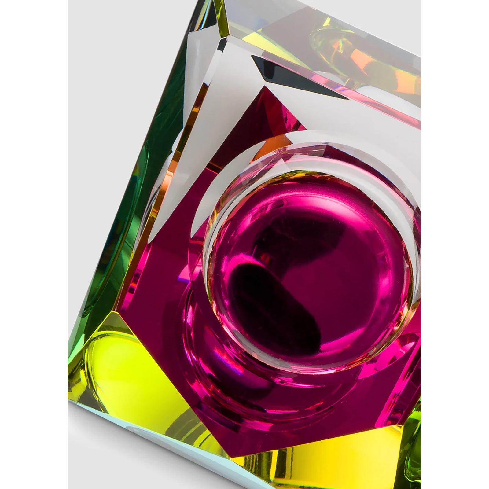 A hand cut solid crystal glass tealight with a colorful dichroic film, displaying a rainbow effect.