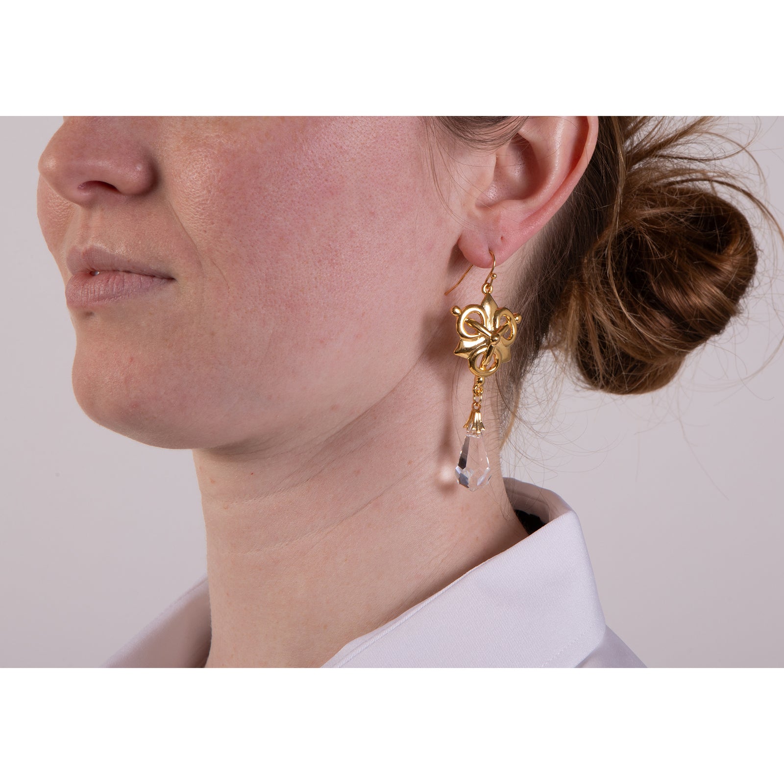 Gold earrings with pearl-like droplets on a white background