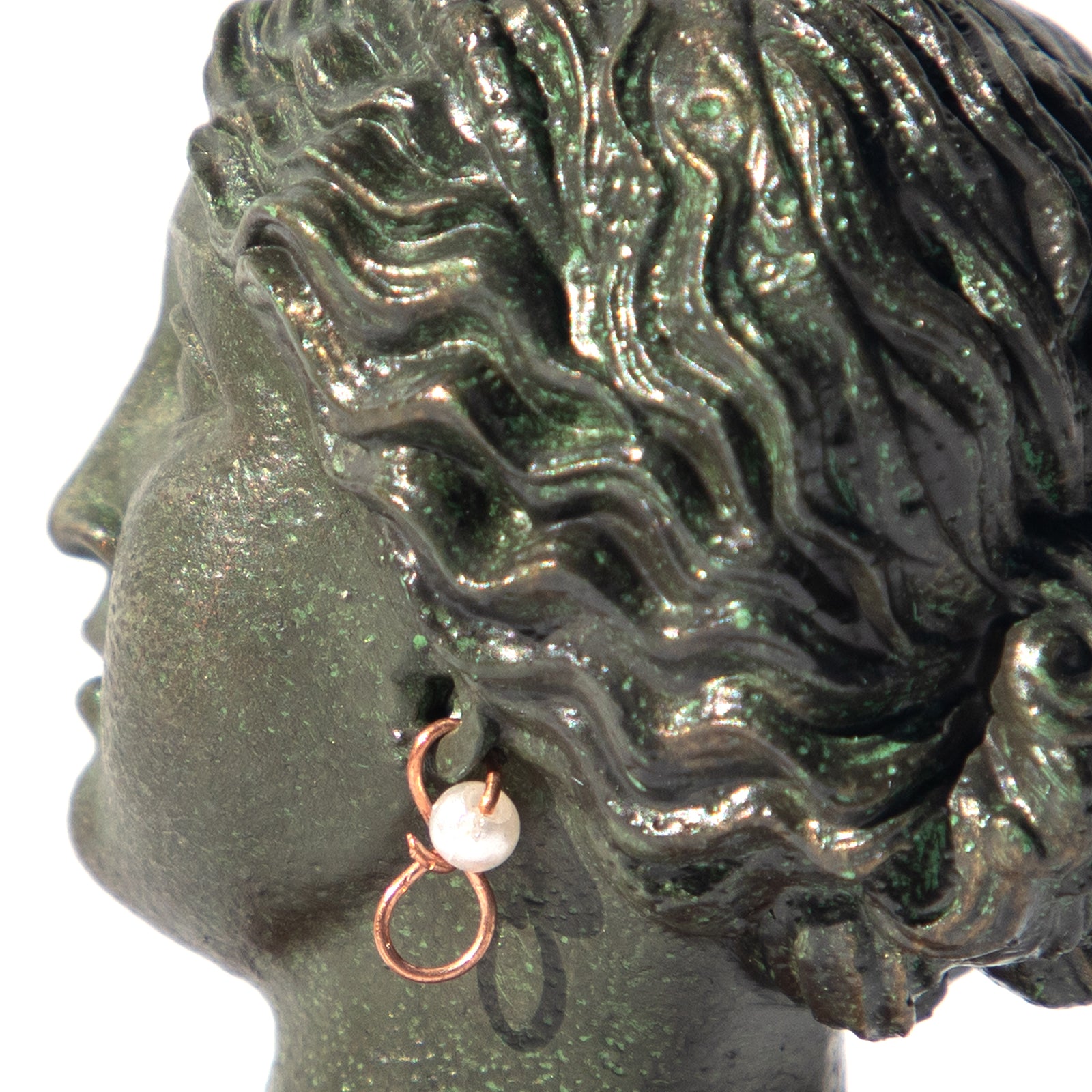 A sculpture reproduction of the Head of Venus with Pearl Earring, placed on a red base, with a greenish tint representing the age-old material.