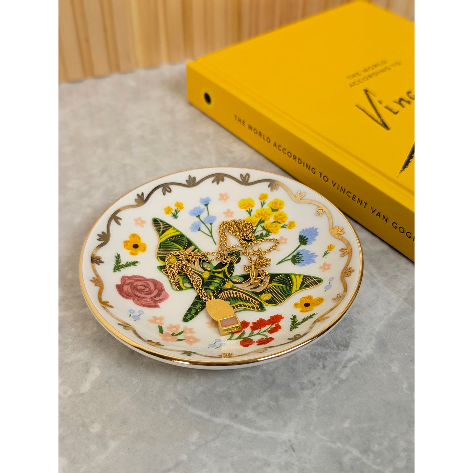 A round porcelain ring dish with a gold rim and multicolored floral patterns in the center.
