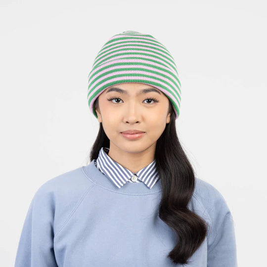 Person wearing a green and lilac striped beanie against a plain background