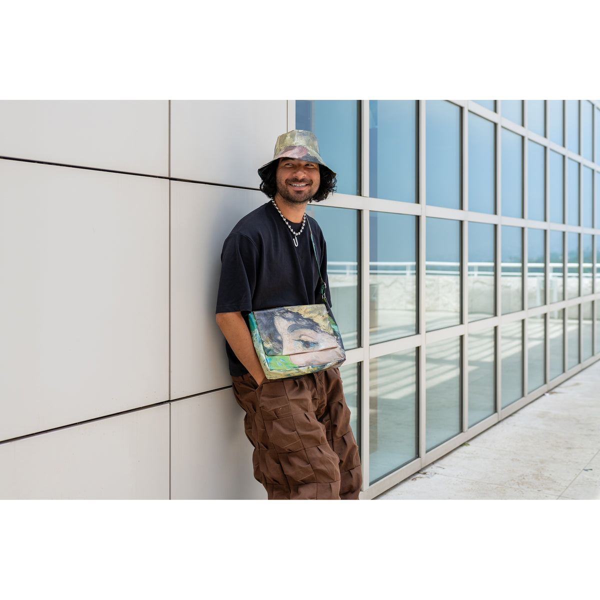 Person holding a colorful bag against a modern building with glass windows.