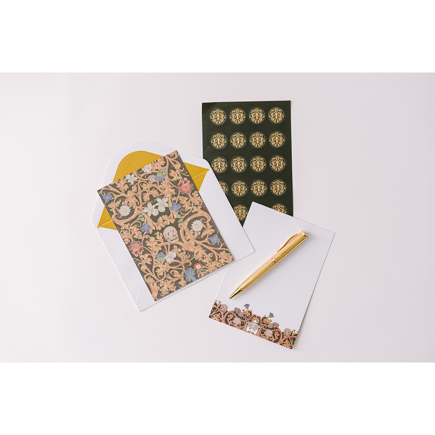 A luxurious stationery set displayed in a gold-foiled keepsake box with a blue ribbon, including gold-toned foil-stamped writing sheets, metallic-lined envelopes, sealing stickers, and a ball-point pen.
