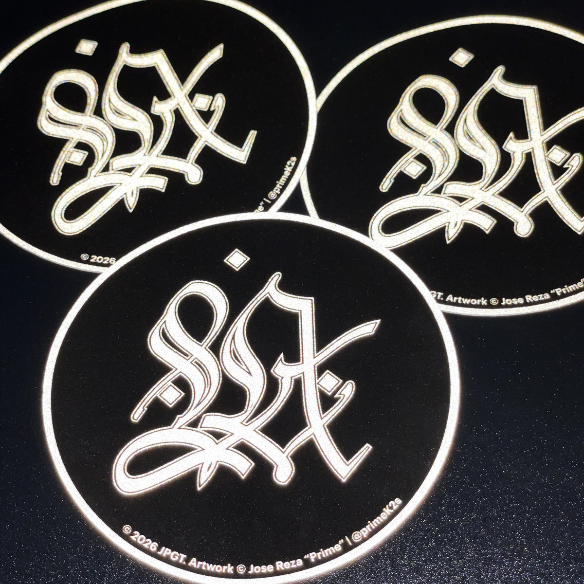 Three circular stickers with stylized text on a black background
