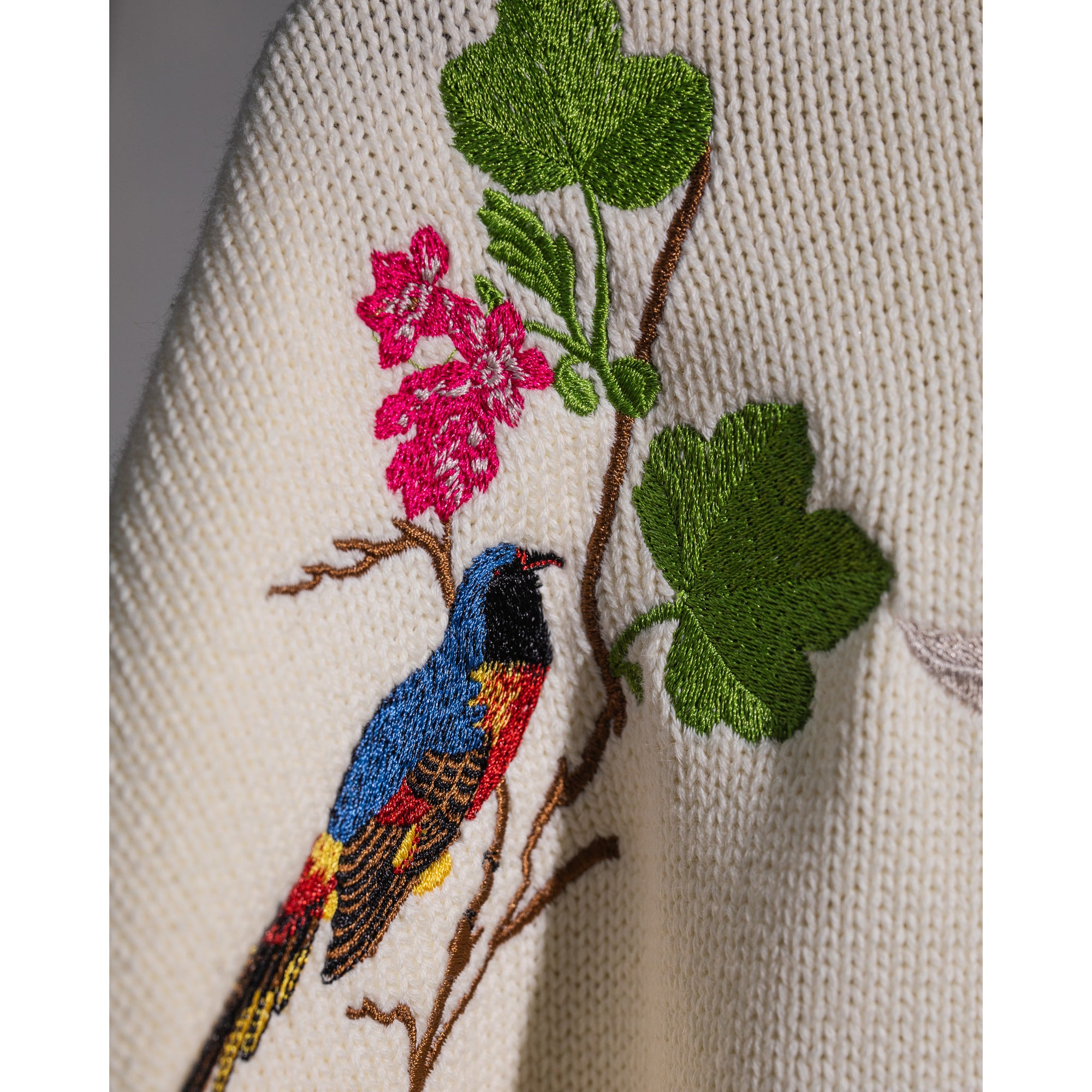 Cream sweater with floral and bird embroidery on a white background
